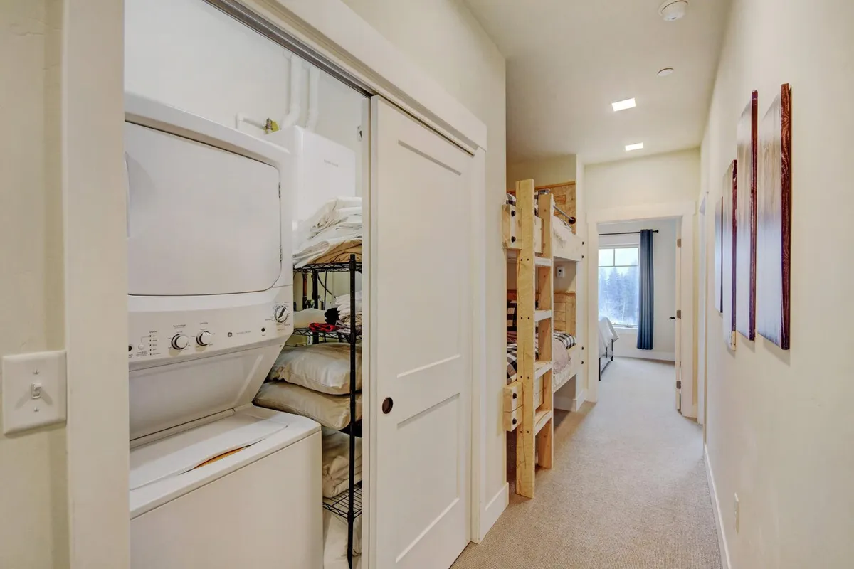 A well-appointed laundry area featuring modern appliances, located adjacent to cozy bunk beds and a window with curtains. The practical layout underscores convenience and comfort, suggesting ease for families or groups traveling together.