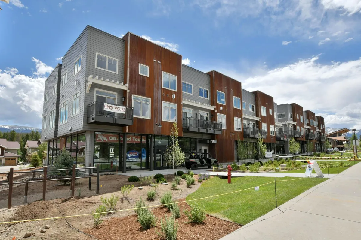 This exterior image features a modern home entrance with an inviting open house sign, surrounded by landscaped greenery. In the background, the scene hints at a welcoming neighborhood environment with families and community spaces.