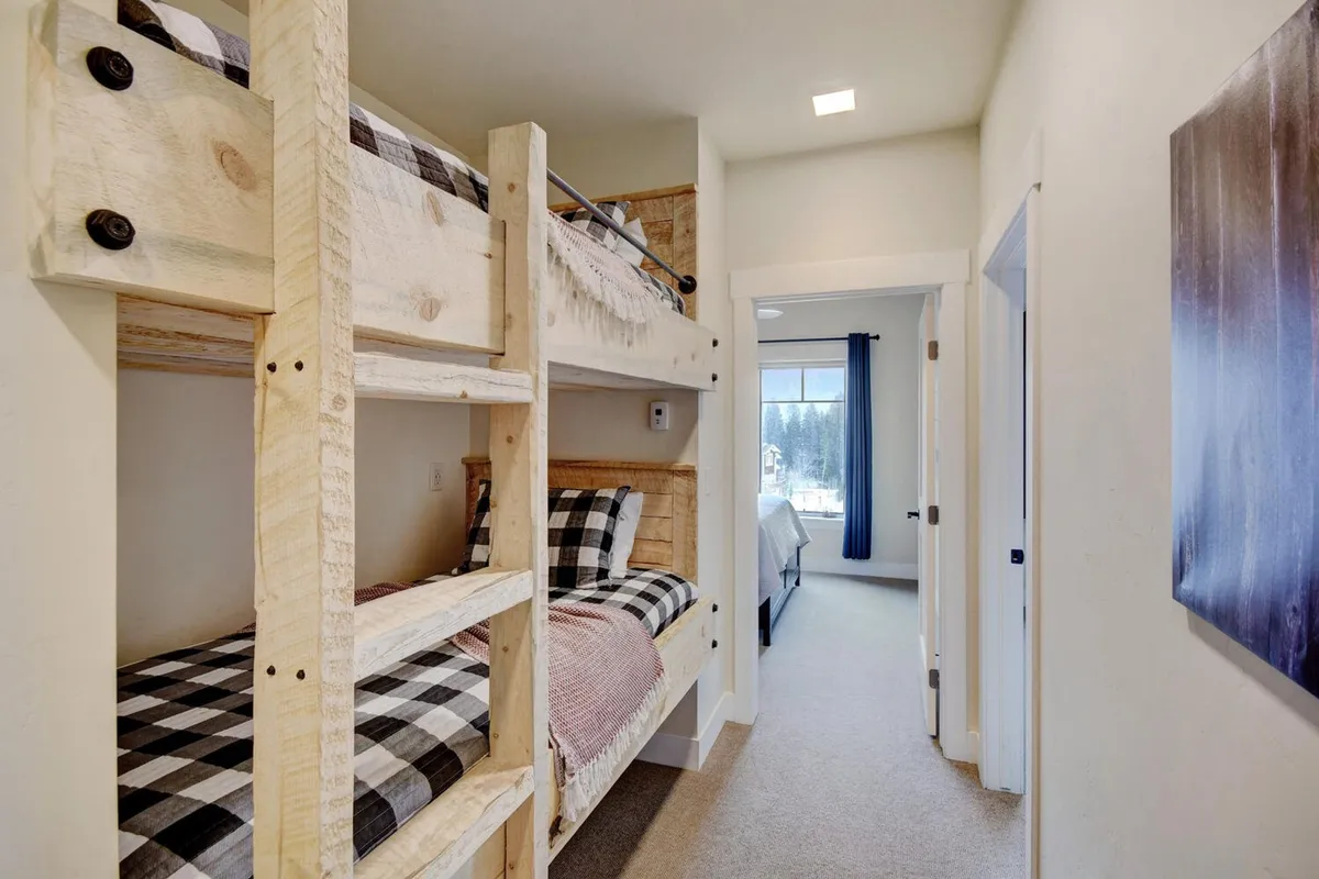 A playful yet refined bedroom with bunk beds, abundant natural light streaming through the window, and charming decor. The space is kid-friendly and flexible for families or groups, encouraging togetherness and bedtime routines.