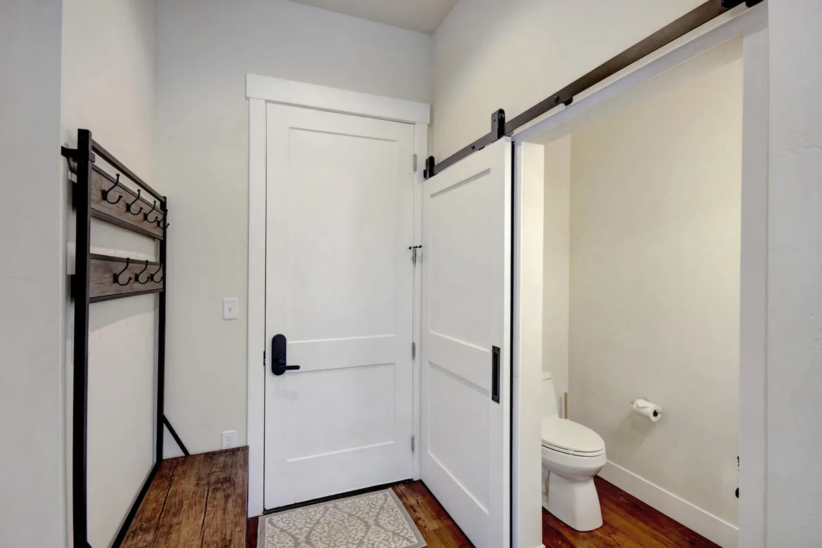 A neatly organized entryway with a coat rack and easy access to a bathroom, designed for efficient transitions as guests come and go. The functional design hints at keyless entry and provides a welcoming first impression.